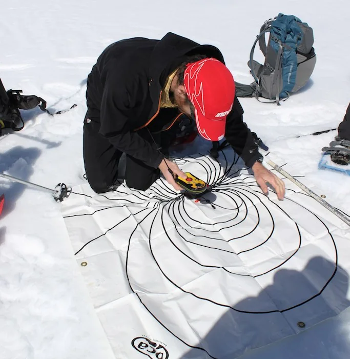 Participant en exercice de recherche avec un détecteur de victimes d’avalanche sur la neige