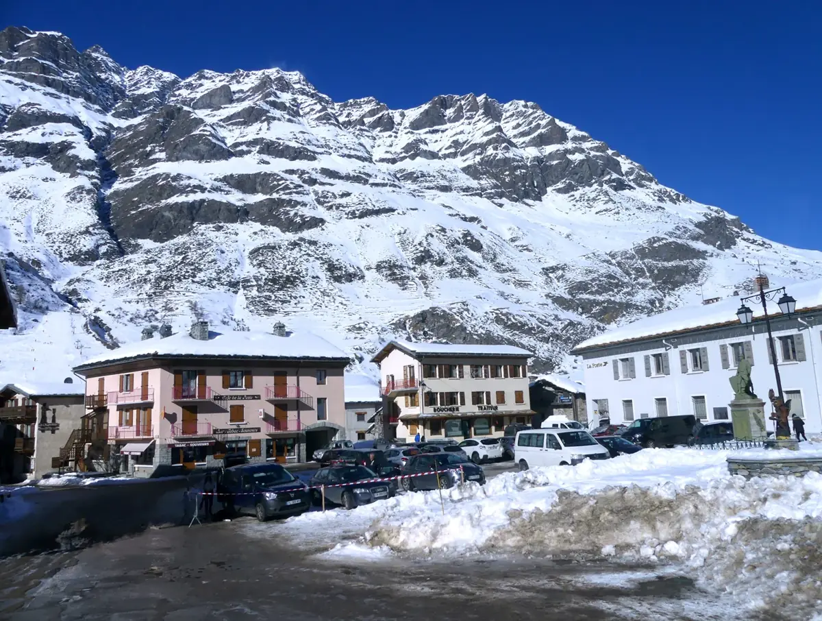 Maisons du centre de Bessans au pied d’une montagne enneigée.