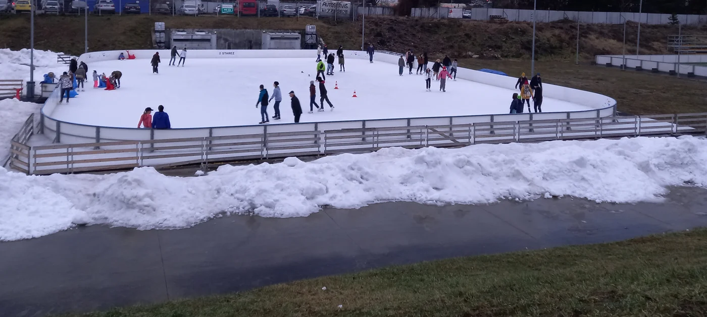 Adultes et enfants patinent sur une piste de glace extérieure à Brno.