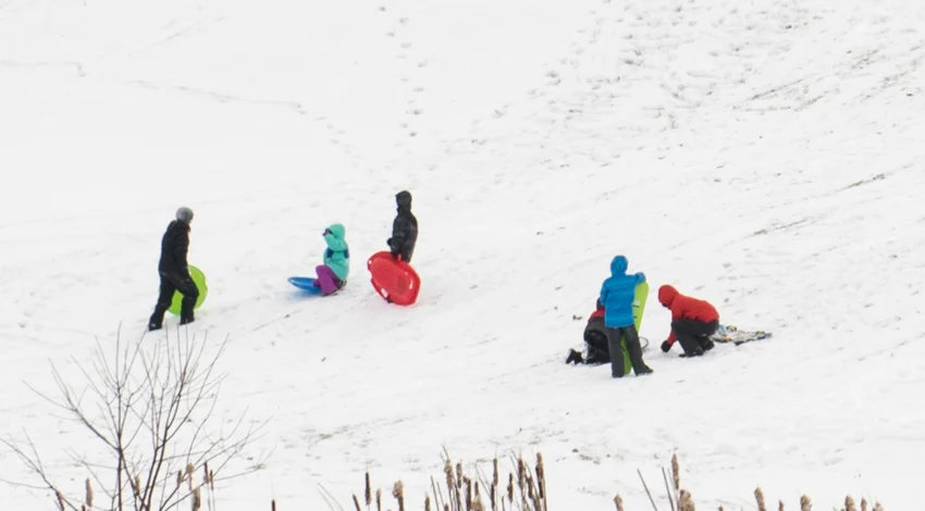 Des enfants sont regroupés avec leurs luges sur une pente enneigée dans le Kentucky.