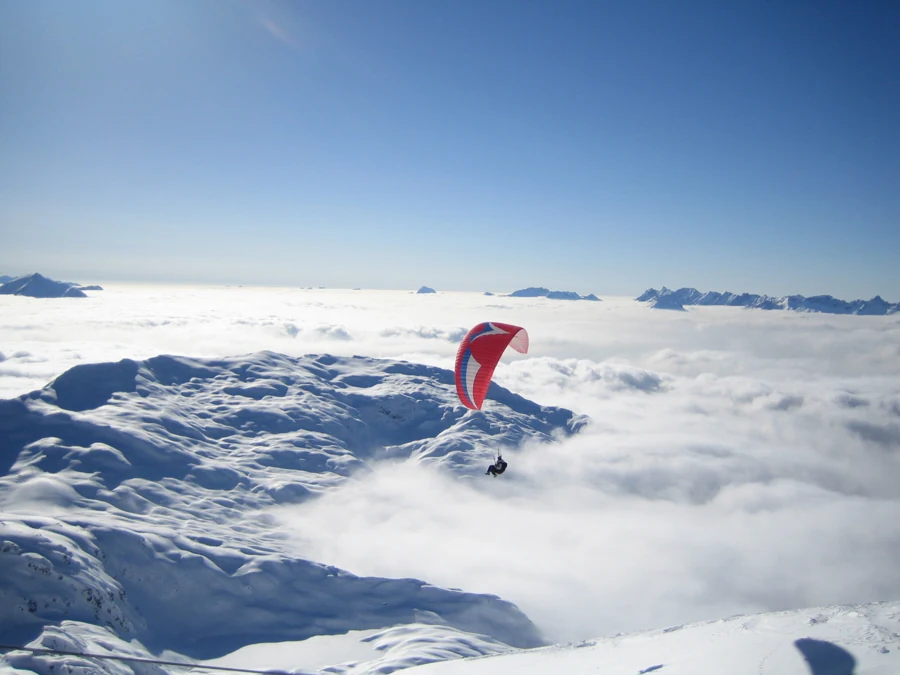 Parapente volant au-dessus d’un paysage enneigé à Chamonix.