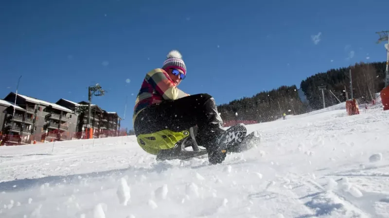 Personne assise sur un yooner et glissant sur une piste enneigée à Plagne Montalbert.